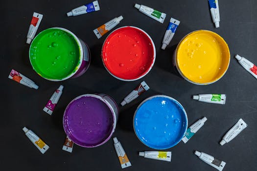 Colorful paint containers and tubes arranged in a flat lay composition from above.